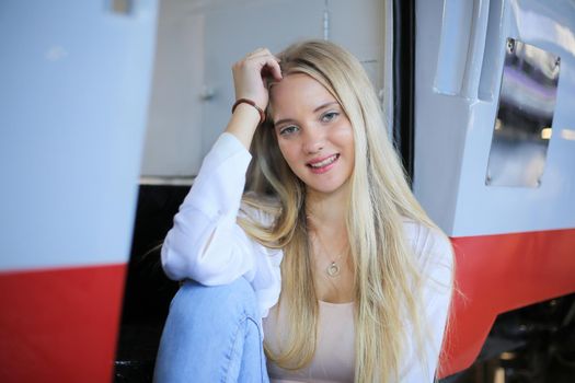 young woman waiting in vintage train, relaxed and carefree at the station platform in Bangkok, Thailand before catching a train. Travel photography. Lifestyle.