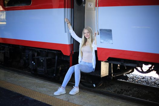 young woman waiting in vintage train, relaxed and carefree at the station platform in Bangkok, Thailand before catching a train. Travel photography. Lifestyle.