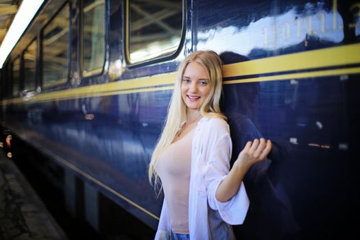 young woman waiting in vintage train, relaxed and carefree at the station platform in Bangkok, Thailand before catching a train. Travel photography. Lifestyle.