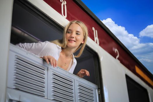 young woman waiting in vintage train, relaxed and carefree at the station platform in Bangkok, Thailand before catching a train. Travel photography. Lifestyle.