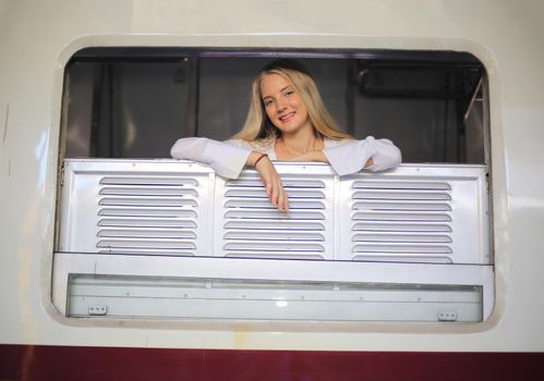 young woman waiting in vintage train, relaxed and carefree at the station platform in Bangkok, Thailand before catching a train. Travel photography. Lifestyle.