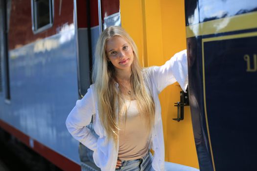 young woman waiting in vintage train, relaxed and carefree at the station platform in Bangkok, Thailand before catching a train. Travel photography. Lifestyle.