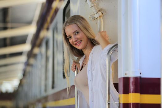 young woman waiting in vintage train, relaxed and carefree at the station platform in Bangkok, Thailand before catching a train. Travel photography. Lifestyle.