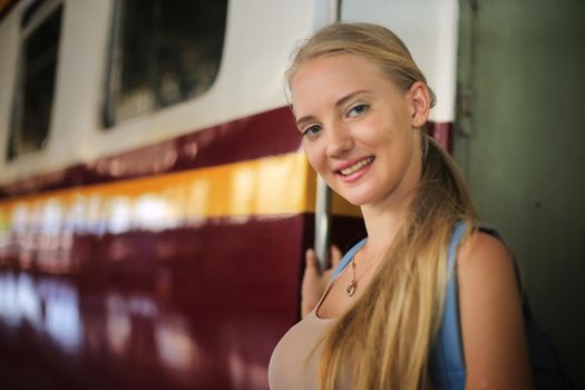 young woman waiting in vintage train, relaxed and carefree at the station platform in Bangkok, Thailand before catching a train. Travel photography. Lifestyle.