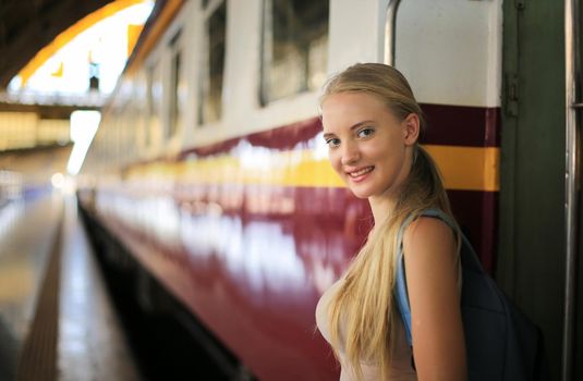 young woman waiting in vintage train, relaxed and carefree at the station platform in Bangkok, Thailand before catching a train. Travel photography. Lifestyle.