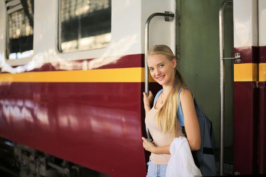 young woman waiting in vintage train, relaxed and carefree at the station platform in Bangkok, Thailand before catching a train. Travel photography. Lifestyle.