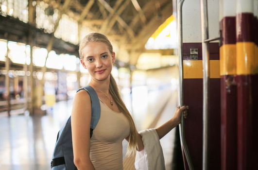 young woman waiting in vintage train, relaxed and carefree at the station platform in Bangkok, Thailand before catching a train. Travel photography. Lifestyle.