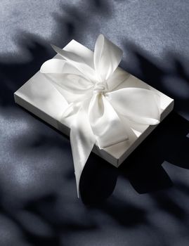 Anniversary celebration, shop sale promotion and luxe surprise concept - Luxury holiday white gift box with silk ribbon and bow on black background, luxe wedding or birthday present