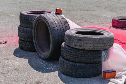 Old worn car tires folded for safety in case of accidents on the race track and covered with polyethylene