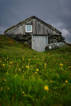 Old outhouse next to main house. Not in use today, is more of a museum object. Called 'Træet på Line'. Nice colors durint the spring time, dark clouds in the horizon.