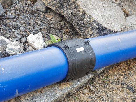 Welded black joint between two blue HDPE tubes for drink water delivery. Repairing of water supply system.