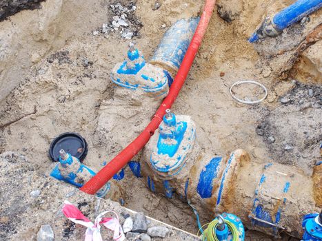 Blue water pipes and shut-off valve on 300mm pipe with  plastic tube branch. Repairing of drink water system. Open excavation pit.