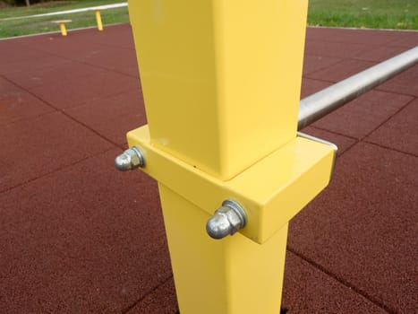 Screwed yellow workout construction on outdoor playground. Steel pole with beam and chrome horizontal bar for acrobatic exercise.