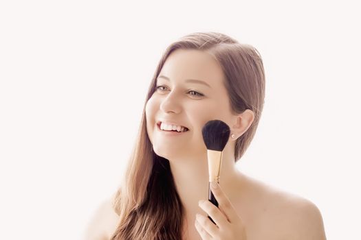 Beautiful woman with makeup brush, perfect skin and shiny hair as make-up, health and wellness concept. Face portrait of young female model for skincare cosmetics and luxury beauty ad design.