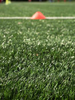 Cones are soccer training equipment on green artificial turf with blurry coach is training kid players background