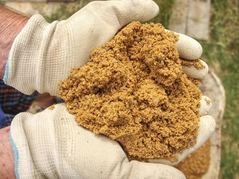 Worker hands in gloves holds sand. Wet yellow sand for building - concept of traditional construction of house. Sand on the hand.