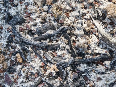 Ground with ash, coals and rusty iron plates on ground of burnt house.