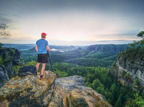 Landscape photographer prepare camera to takes impressive photos of misty fall mountains. Tourist photographer at sharp rocky edge