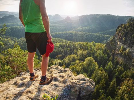 Green singlet and black pants fearless boy in rocks. Amazing view into wild nature landscape.