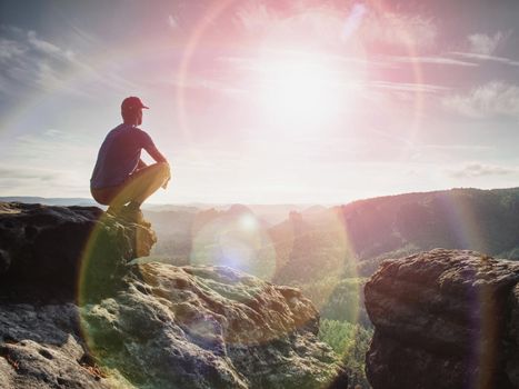 Man sitting on the rock cliff in mountain and watching on sunrise landscape. Nature composition.