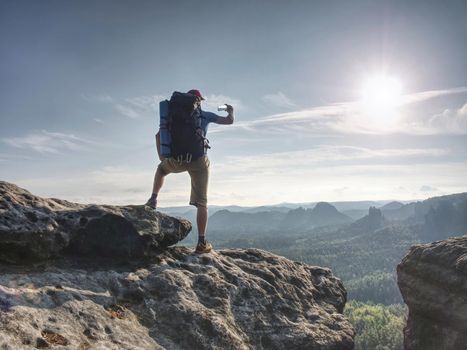 Man with smart phone. Rear shot of man taking photo of mountain with smartphone