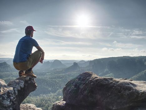 Successful man raising body on the cliff with the blue jersey, sunny blue sky in  background