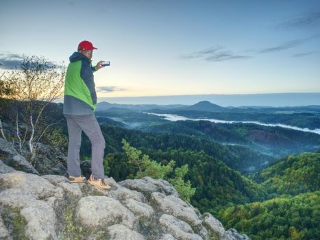 Moment of daybreak. Man on rocky trail stop to enjoy view to morning sun, silhouette on the rock 