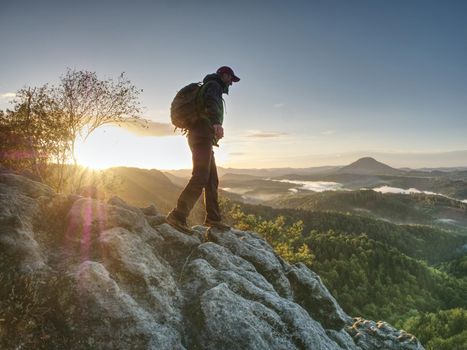 Moment of daybreak. Man on rocky trail stop to enjoy view to morning sun, silhouette on the rock 