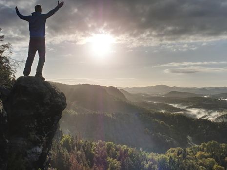 Traveler on mountain summit enjoying aerial view over misty countryside. Travel Lifestyle success adventur