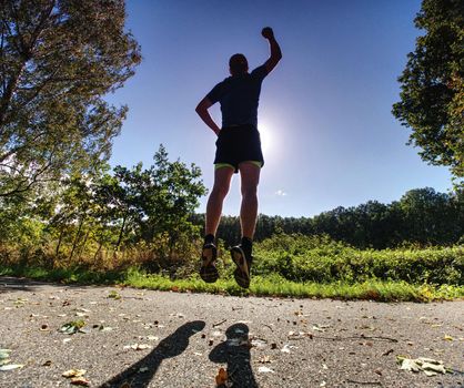 Action man, full of strength sportsman wearing shorts and sneakers, he is running a marathon, 