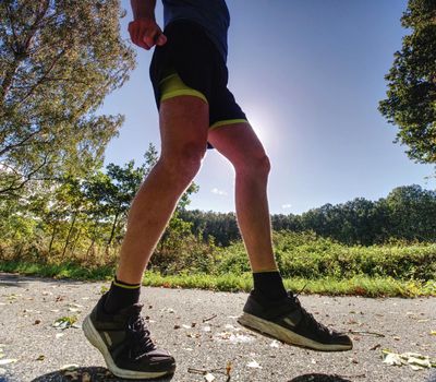 Man excercise. Male fitness athlete jogger workout in wellness concept. Hot sun in background
