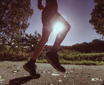 Side silhouette of active man exercising and running on the road  at sunrise. Healthy lifestyl