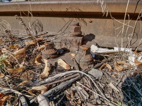 ap with nut and screw on the old rusty rail. Rusty train railway detail, oiled sleepers and stones between rail way 