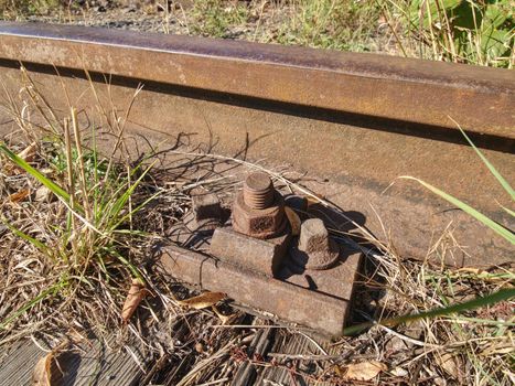 ap with nut and screw on the old rusty rail. Rusty train railway detail, oiled sleepers and stones between rail way 