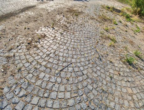 Old ruin coblestone road. Stone pavement texture. Granite cobblestoned pavement