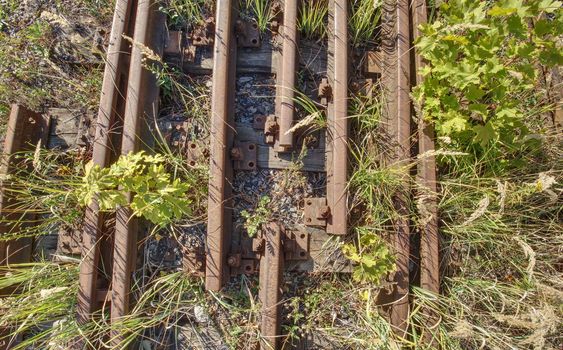 Old abandoned rail and bolt of a railway.  Rusty train railway detail, oiled sleepers and stones between rail way 