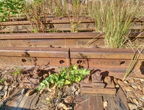 Detail of rusty screws and nut on old railroad track. Rotten tie with rusty nuts and bolts. Terrible smell extracted old wooden ties with phenol asphalt paint.