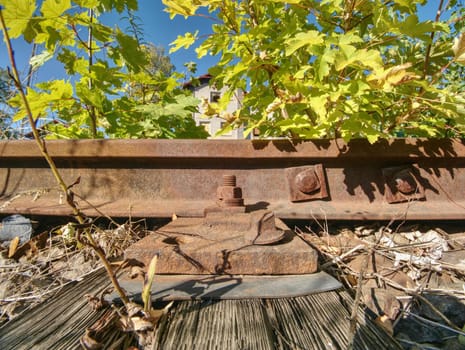 Detail of rusty screws and nut on old railroad track. Rotten tie with rusty nuts and bolts. Terrible smell extracted old wooden ties with phenol asphalt paint.