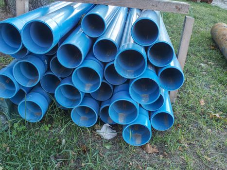 Bundles of blue plastic pipes for water transport. Pipe batch construction site.