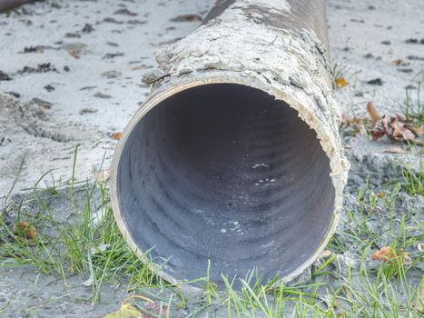 Long metal industrial pipes laying on ground. Repairing of the water delivery system. Open trench with water pipe and heap of ground near.