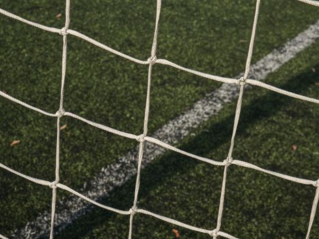 Frame of football gate, white gate net on background of a green football field