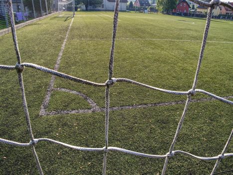 Soccer or football corner lines through safety net. View from behind the tribune net with blurred stadium and field pitch