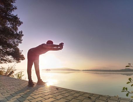 Middle aged runner stop for breath. Sportsman takes a break and looking to morning Sun above horizon