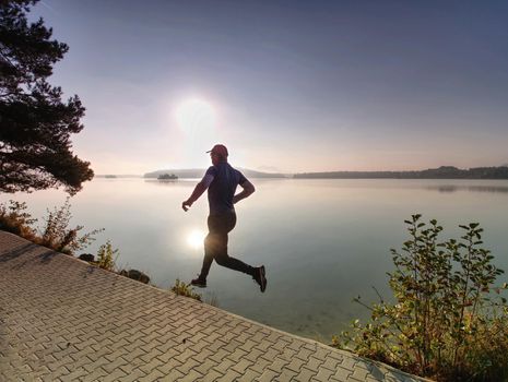 Silhouette of athlete run on sunset background copy space. Man with sportive figure practices sport running for life. Sport and training concept.