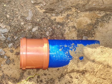 Laying of  HDPE pipe underground of City portable water system. . Blue plastic pipe with orange brown technological cover in sandy trench.