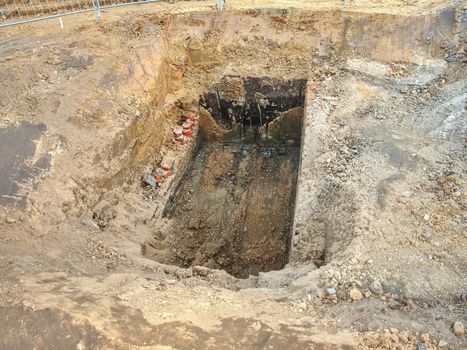 Open trench with small diameter water pipe and heap of ground near. Excavation of trench by hand or mechanized excavator and installation.