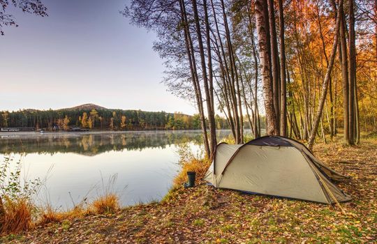 View over man body in camping tent to lake in beautiful morning. Enjoy freedom in pure nature.