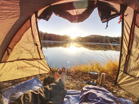 Couple legs rest in tent at lake. Hiker enjoy  view outsid and e free hike vacation