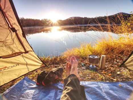 Couple legs rest in tent at lake. Hiker enjoy  view outsid and e free hike vacation