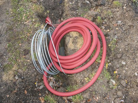 Thin  diameter ribbed  orange PVC pipe in the ground before laying